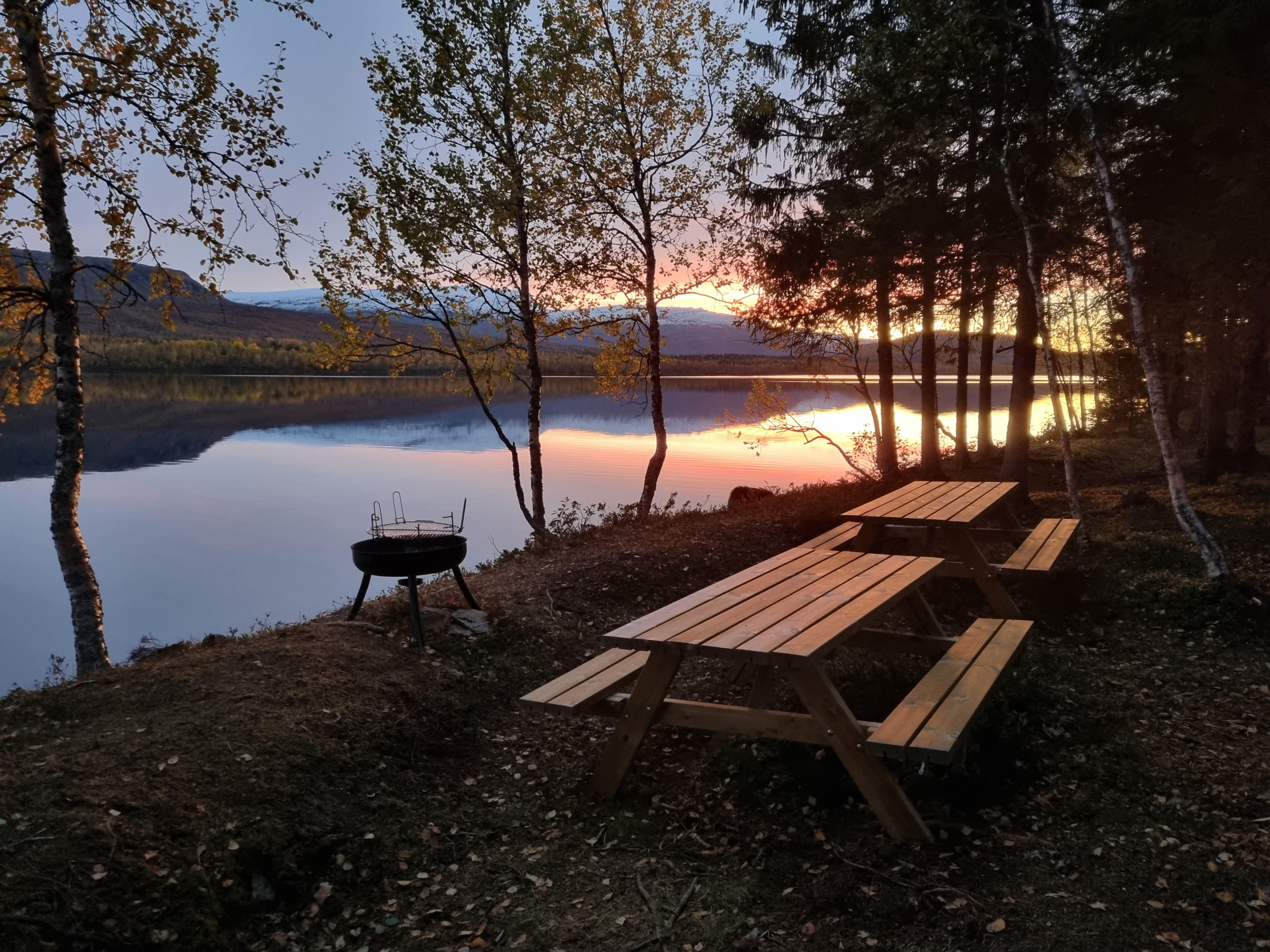 Sittebenker ved et vann i solnedgang